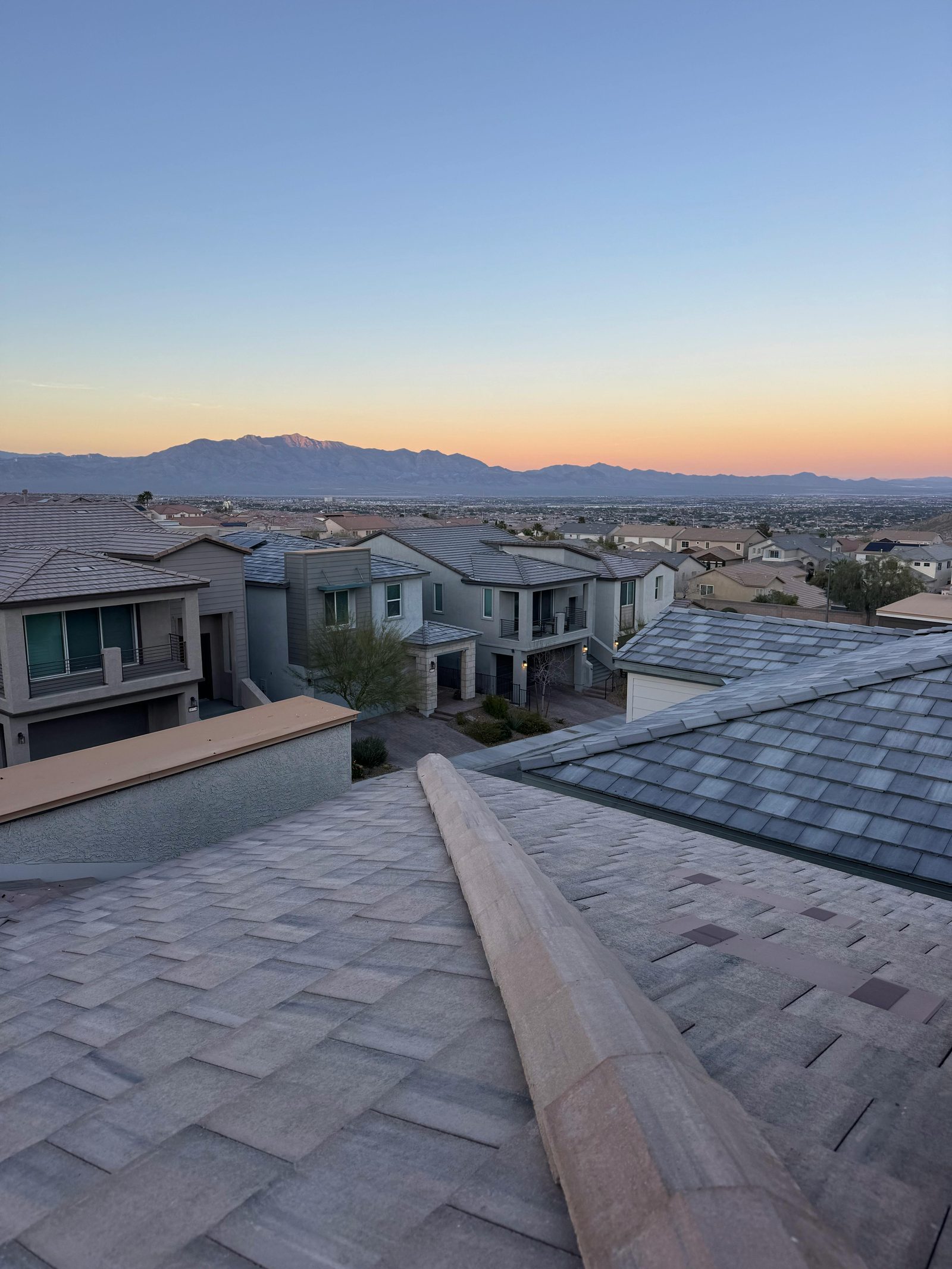 Arizona neighborhood at golden hour with tile and shingle roofs and mountain views in the distance